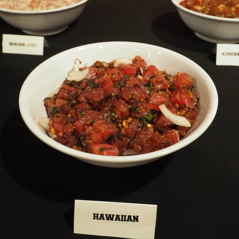 Bowl of Hawaiian-style diced raw tuna seasoned with herbs, spices, onions, and garlic on a black table.